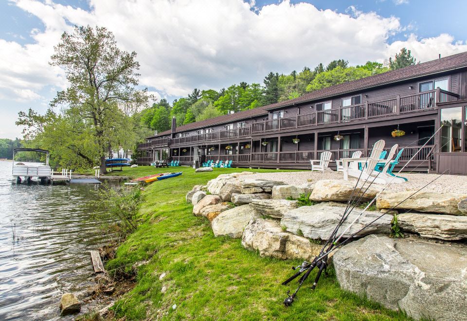 a large building with multiple balconies is surrounded by rocks , grass , and trees near the water at The Black Swan Lee - Lenox, Ascend Hotel Collection