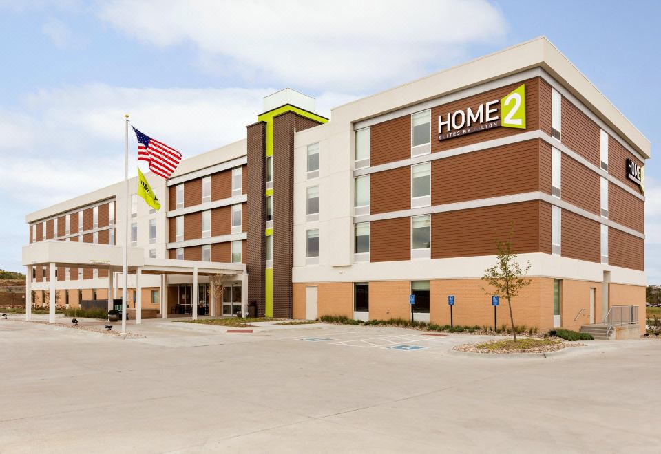 "a large hotel building with a sign that reads "" home 2 "" prominently displayed on the front" at Home2 Suites by Hilton Omaha/West