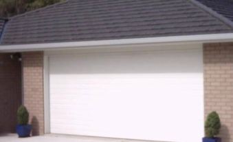 a white garage door is set up in front of a house with a car parked nearby at Number Twelve
