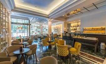 a modern lounge area with yellow chairs , marble floors , and a bar , all set against a backdrop of white ceiling and windows at NH Madrid Nacional