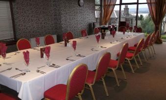 a long dining table set for a formal event , with red chairs and white tablecloths at Richmond Park Hotel