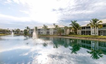 a large body of water surrounded by apartment buildings , with a fountain in the foreground at GreenLinks Golf Villas at Lely Resort