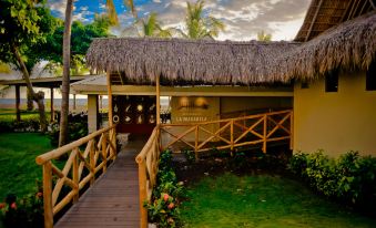 a tropical resort with a thatched roof , palm trees , and a wooden walkway leading to the entrance at Fiesta Resort All Inclusive Central Pacific - Costa Rica