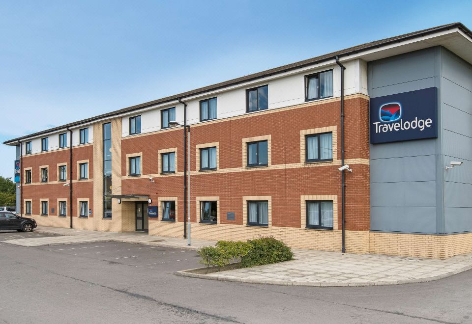 "a large building with a red brick exterior and a blue sign that says "" travelodge .""." at Travelodge Glenrothes