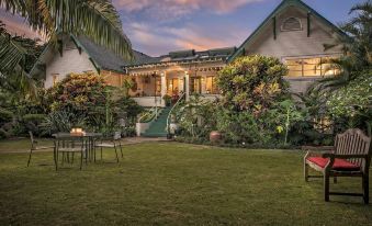 a large house surrounded by a lush green lawn , with a man standing in the grass at The Old Wailuku Inn at Ulupono