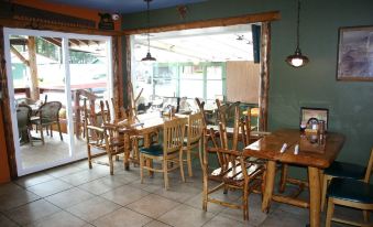 a restaurant with wooden tables and chairs , a green wall , and a glass door leading to an outdoor seating area at Lone Fir Resort