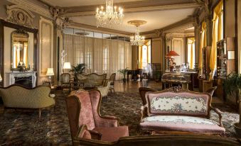 a luxurious living room with ornate furniture , including sofas and chairs , arranged around a dining table at Grandhotel Giessbach