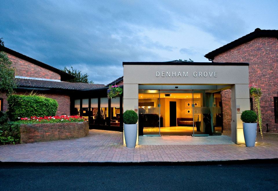 the exterior of a denman grove hotel , with its name displayed in black letters on the front at Denham Grove