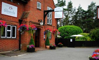 a brick building with potted plants and flowers in front of it , creating a welcoming atmosphere at Baskerville