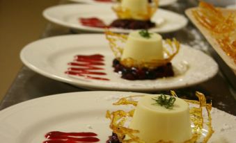 a long row of white plates filled with various desserts , including pies , tarts , and cakes at Grange Burn Motel