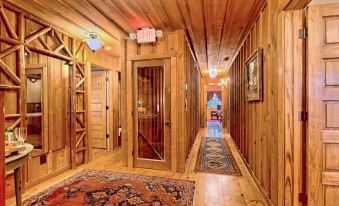 a long hallway with wooden walls and a red carpet leads to a door at the end at Lake Rabun Hotel