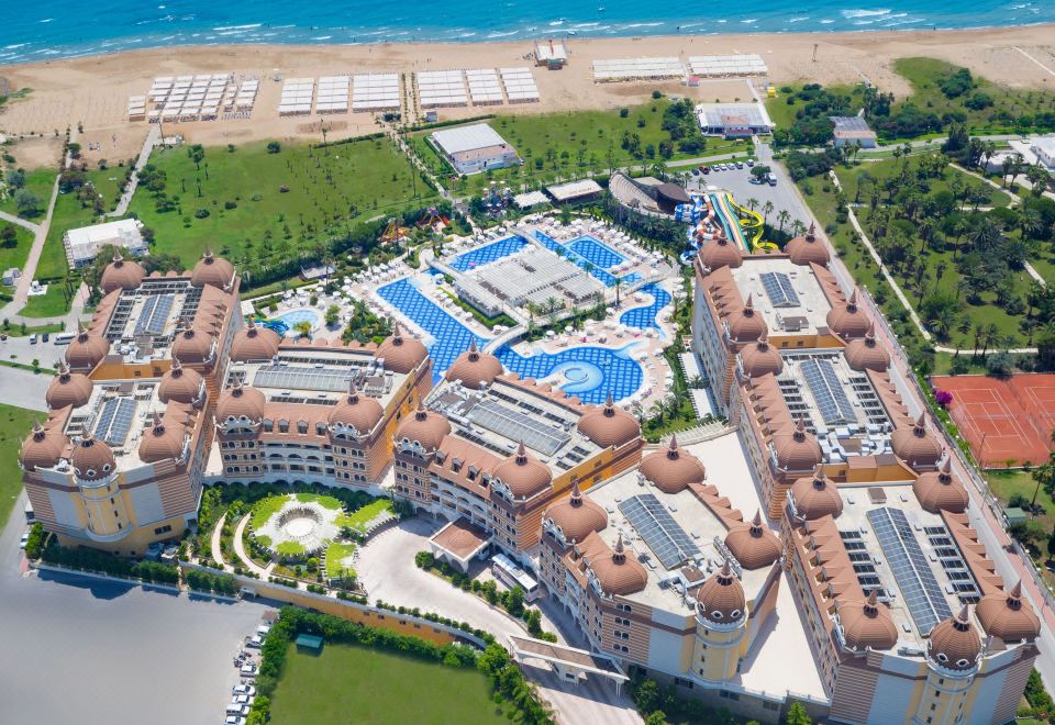 aerial view of a large resort with multiple buildings , swimming pools , and tennis courts near the ocean at Royal Alhambra Palace