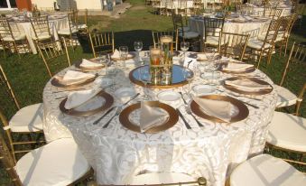 a large round table is set with white and gold plates , napkins , and a vase of flowers at Atami Escape Resort