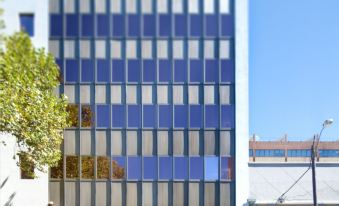a tall , modern building with a blue glass facade and a white facade is located on a city street at 57Hotel