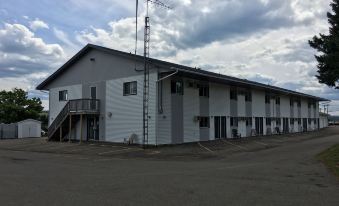 a white building with a metal roof and windows , surrounded by a parking lot under a cloudy sky at Fairway Inn