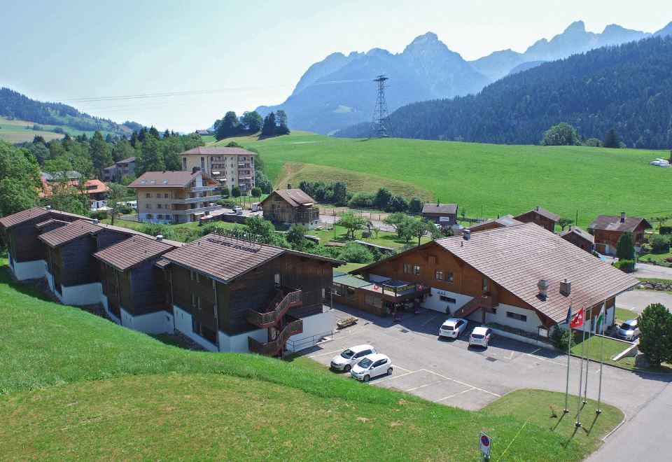 a picturesque mountainous landscape with a small village nestled in the valley , surrounded by lush green grass and trees at Hotel Roc et Neige