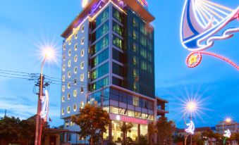 a large , modern hotel building with multiple floors and brightly lit windows , situated on a busy street at dusk at Amanda Hotel