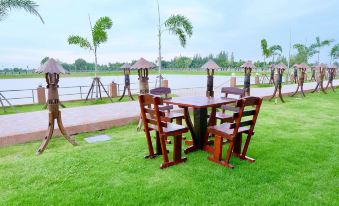 a wooden dining table and chairs set up in a grassy area near a body of water , possibly a lake or ocean at Infinity See Sun Resort