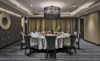 a formal dining room with a round table surrounded by chairs and a chandelier hanging from the ceiling at Carlton Hotel