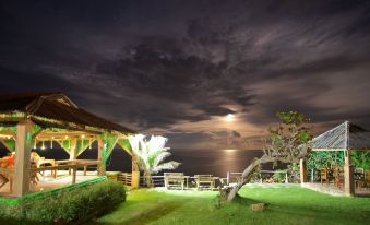 a tropical hut surrounded by lush greenery and a large body of water , illuminated by the moonlight at The Sea Cliff Hotel Resort & Spa