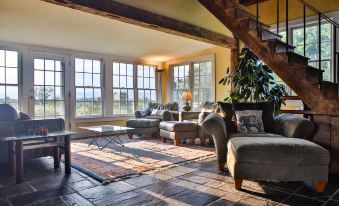 a spacious living room with multiple couches , chairs , and a large window overlooking a beautiful view at Whitford House