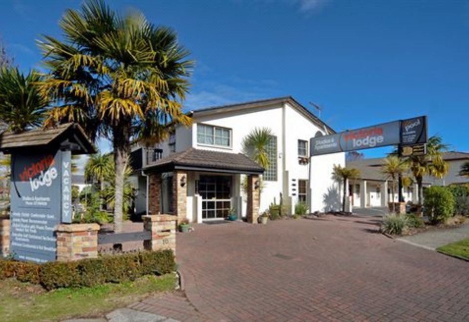 "a white building with palm trees in front of it and a sign that says "" bowling green .""." at Victoria Lodge