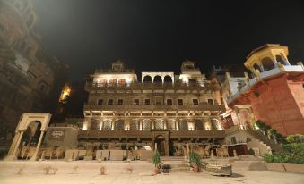a grand , multi - story building with multiple balconies and arches is illuminated by lights at night at Guleria Kothi at Ganges