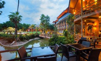 a large hotel with a pool and outdoor dining area is surrounded by lush greenery at Blues River Resort