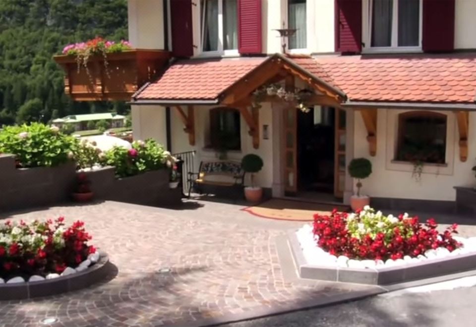 a red roof house with a white entrance and two large flower pots in front at Hotel Olympia