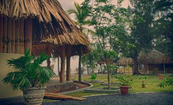a tropical setting with a thatched - roof building surrounded by lush greenery , including palm trees and cacti at Royal Beach