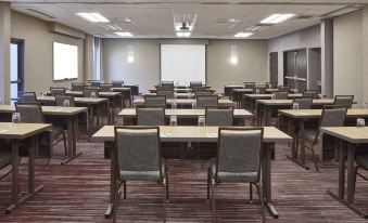 a large conference room with multiple rows of tables and chairs arranged for a meeting or training session at Sonesta Select Raleigh Durham Airport Morrisville