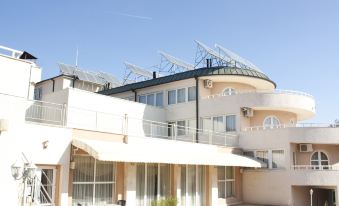 a large building with a satellite dish on top is surrounded by chairs and tables at Park Hotel Bellevue