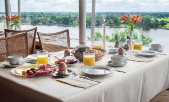 a table is set with breakfast items , including eggs and toast , overlooking a body of water at Hotel Bellevue