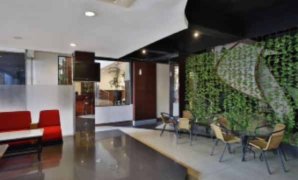 a modern lobby with a green wall , wooden ceiling , and a reception desk , as well as several chairs and tables at Jayakarta Hotel Jakarta