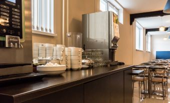 a hotel room with a kitchen area featuring a counter with stacks of bowls and a coffee maker at Petro Sport Hotel