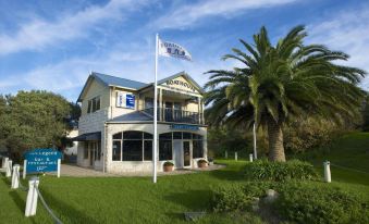 a large house with a flag flying in front of it , surrounded by grass and trees at Boathouse Resort Studios and Suites