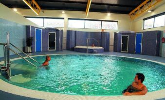 two people are swimming in a large indoor pool , surrounded by blue tile walls and yellow accents at Hotel Los Angeles