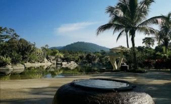 a serene landscape with a mountain in the background , palm trees , and a pool of water in the foreground at Felda Residence Hot Springs