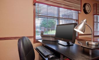 a computer desk with a monitor , keyboard , and mouse is situated next to a window at Residence Inn West Springfield