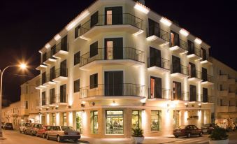 a modern building with balconies and cars parked in front , lit up at night against a dark sky at Hotel Loar Ferreries