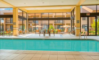 a large swimming pool is surrounded by chairs and tables in a room with a glass wall at Courtyard Chicago Deerfield