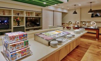 a modern kitchen with wooden cabinets , a buffet table filled with various food items , and a television mounted on the wall at Holiday Inn Roswell