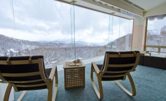 a room with two chairs and a small table in front of a large window overlooking a snow - covered mountain at Arcadia