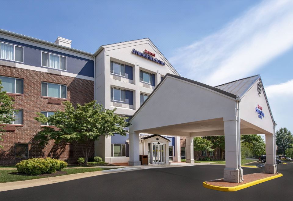 a fairfield inn & suites by marriott hotel with its entrance and parking lot , under a clear blue sky at SpringHill Suites Herndon Reston