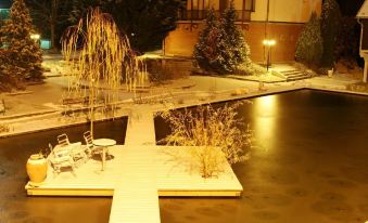 a serene nighttime scene of a pond with a dock , chairs , and a bench , surrounded by trees and illuminated by streetlights at Waterfront