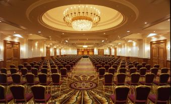 a large conference room with rows of chairs arranged in a semicircle , and a chandelier hanging from the ceiling at The Keadeen Hotel