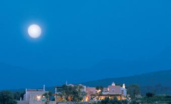 a large house with a full moon shining above it , surrounded by trees and mountains at Grecotel Plaza Beach House