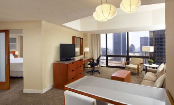 a hotel room with a large flat - screen tv mounted on the wall , a desk , and a chair at The Westin Bonaventure Hotel & Suites, Los Angeles