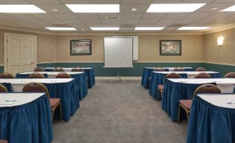 a conference room with rows of tables and chairs , a projector screen at the front , and framed art on the walls at Sonesta ES Suites San Francisco Airport San Bruno