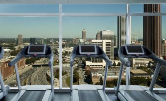 a modern gym with three treadmills facing a large window offering a view of a city skyline at W Atlanta – Downtown